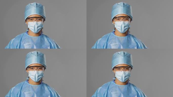 灰色背景下戴着安全眼镜和面罩的微笑女外科医生的肖像
