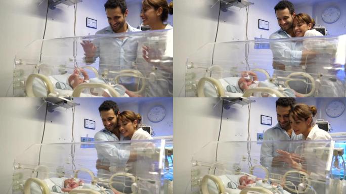 幸福的夫妇在新生儿重症监护病房非常亲切地看着他们的新生儿