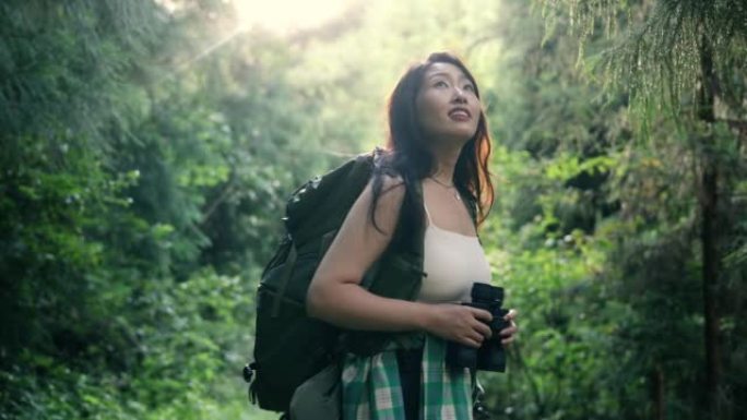 年轻女子在森林里用双筒望远镜