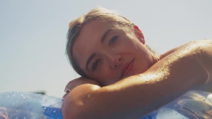 暑假的女人在游泳池里漂浮的充气充气床上放松
