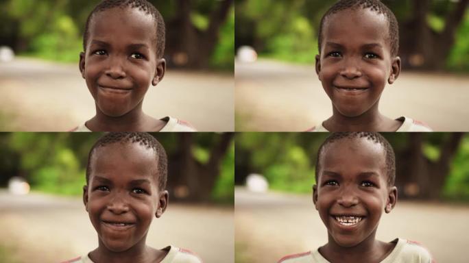 一个害羞的真实的非洲男孩在镜头前微笑，背景是一个模糊的乡村。黑人男孩代表未来、希望和接纳。纪录片镜头