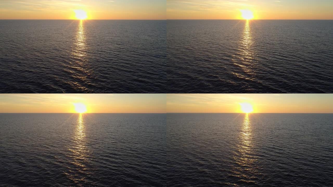 日落时飞越海面或洋面。夕阳在水中反射形成一条黄金路径。空中无人机射击