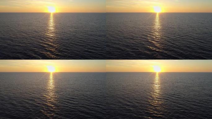 日落时飞越海面或洋面。夕阳在水中反射形成一条黄金路径。空中无人机射击
