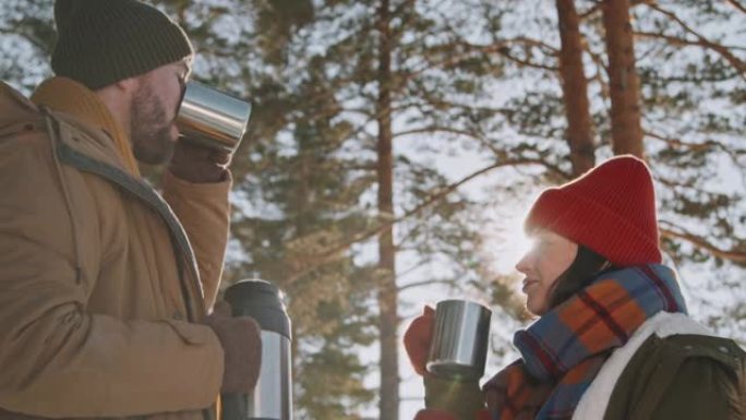 男人和女人在冬季森林里享受热茶