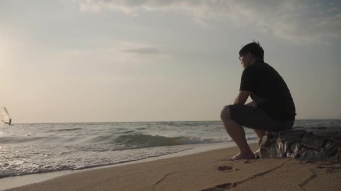 亚洲男子郁闷独自坐在海边