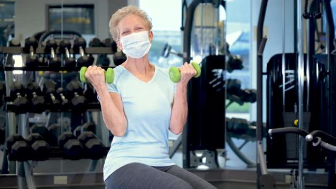 在健身房锻炼的高级妇女，戴着口罩