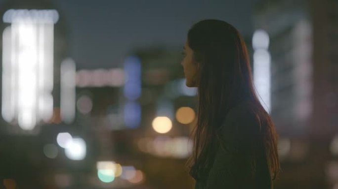 4k视频片段，晚上一名妇女在城市的屋顶上