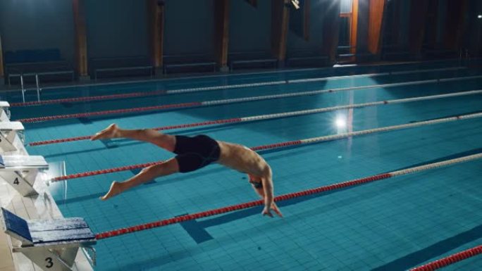 肌肉发达的男性游泳运动员在游泳池潜水。职业运动员优雅地跳跃。决心赢得冠军的训练。电影光线，时尚色彩的