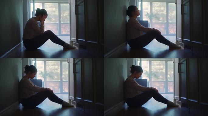 悲伤的年轻女子坐在公寓的墙上，用手遮住脸。抑郁的气氛关系中的麻烦，家庭中的死亡。戏剧性的 “坏消息”