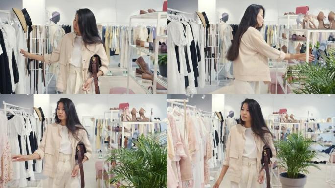 迷人的亚洲女孩在现代时尚精品触摸服装中选择服装