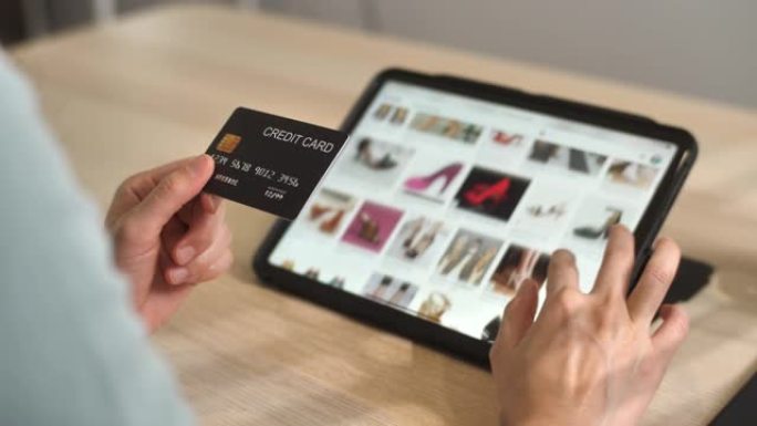 特写手女人的手拿着信用卡在网上网站商店购物在线支付购买在家里的数字平板电脑上