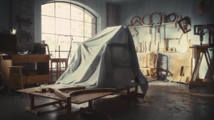 建立镜头: 在木工车间正式展示之前，隐藏在面纱下的设计师椅子。放大布套下时尚扶手椅的照片。