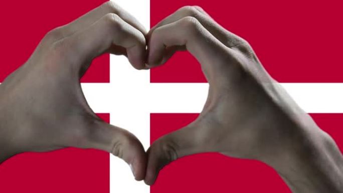 双手在丹麦国旗上显示心脏标志。