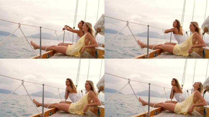 在阴天，两个满意的女人一起坐在船上。快乐的朋友一起在游艇巡游中欣赏海景。两个朋友一起享受巡游