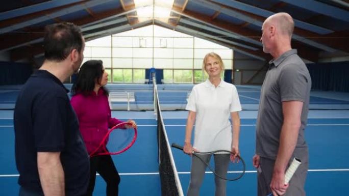 穿着运动服的快乐高级男女在网球场上聊天