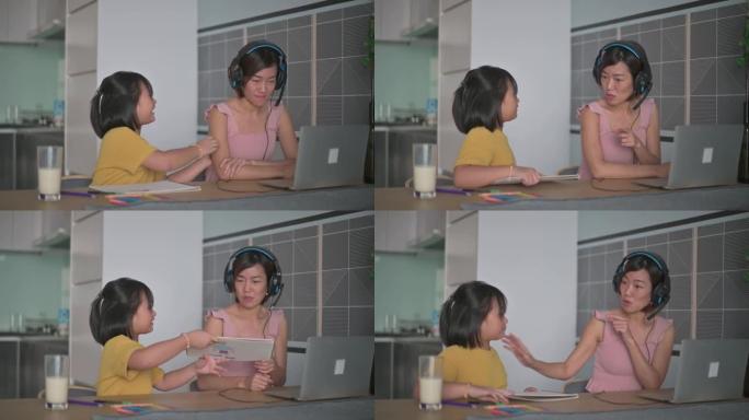亚洲华裔女商人在家与同事进行视频通话，而女儿在餐桌上做作业