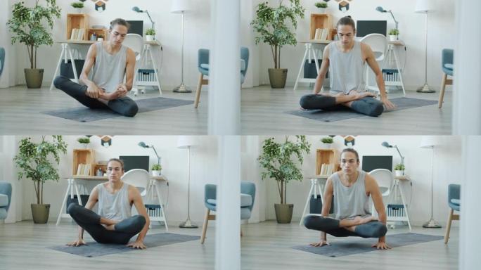 年轻的运动员在家里独自坐在瑜伽垫上锻炼，保持手臂平衡。