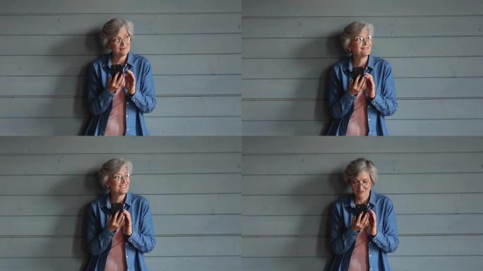 木墙工作室背景用智能手机摆姿势老年女性