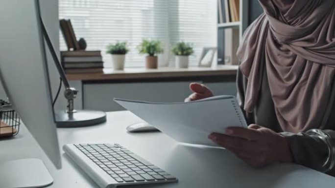 女人的手拿着抄写本和计算机上的视频通话