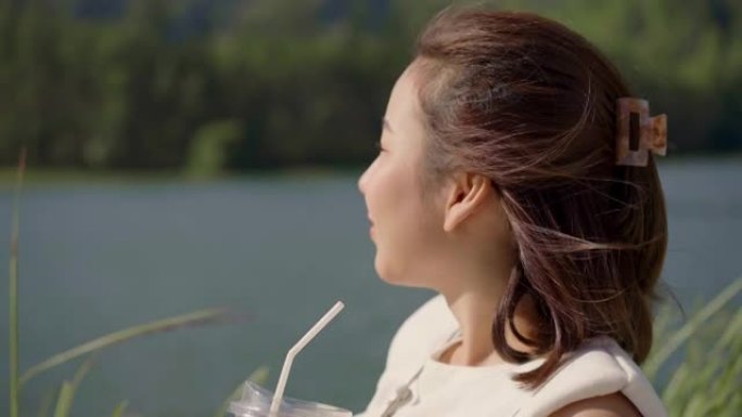 时髦的女人在湖边喝最喜欢的饮料放松。