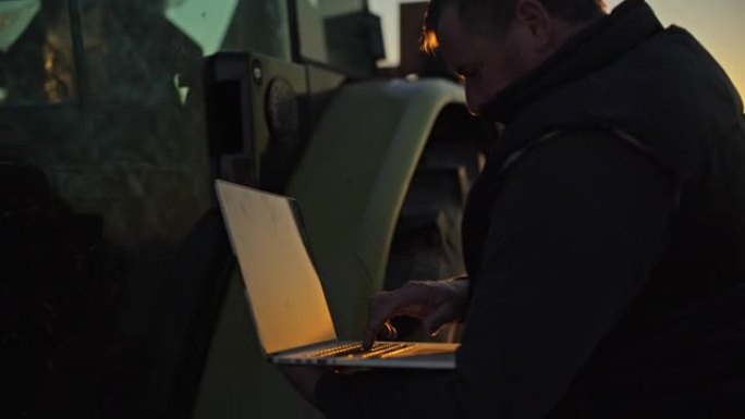 男性农民在日出时在寒冷的农村地区的笔记本电脑上工作