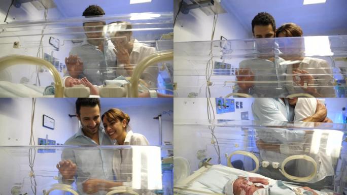 拉丁美洲幸福的父母在NICU的孵化器中看着他们漂亮的婴儿