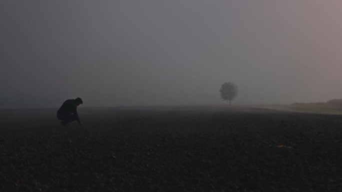 农民走过田野，检查雾中的生长