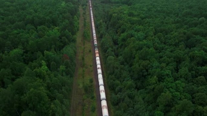 火车在原始生态绿色森林中运送原油罐。鸟瞰图。