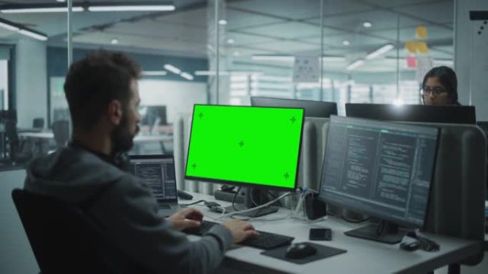 多民族办公室: 使用绿屏色度键显示在计算机上工作的IT程序员。男软件工程师开发应用程序，程序，视频游