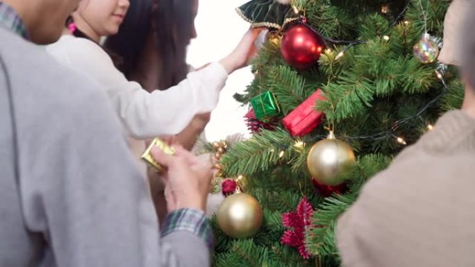 4K UHD多莉拍摄多代亚洲幸福家庭装饰圣诞树与装饰品一起为节日快乐冬天做准备。