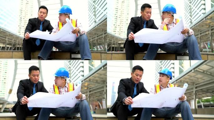 商人和工程师正在使用纸质蓝图讨论该项目。作为高层建筑大城市场景背景下的交流工具