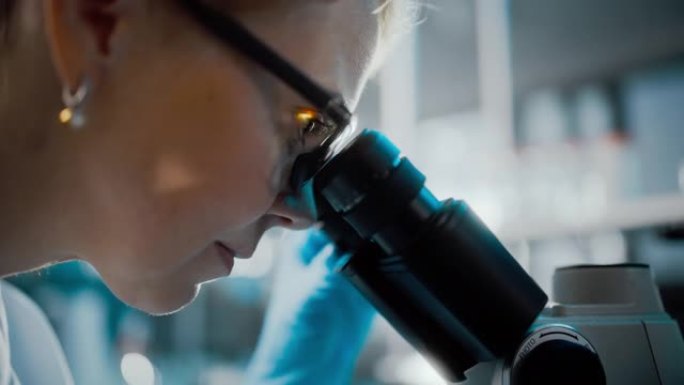 在明亮的医学科学实验室: 美丽的微生物学家戴着眼镜在显微镜下观察分析样品。杰出的科学家，医生，使用高