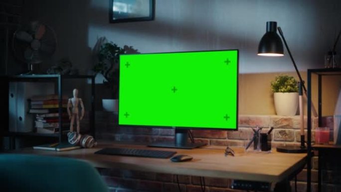 绿屏电脑显示器站在木桌上，具有高度可调功能。现代客厅或带砖墙的创意阁楼办公室的家里色键显示。放大镜头