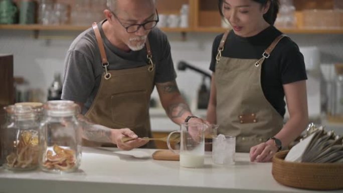亚洲华裔高级男咖啡师在咖啡厅柜台教女儿煮咖啡