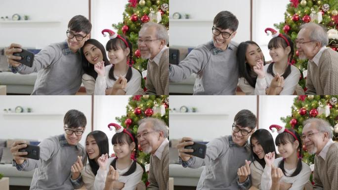 检疫快乐的亚洲家庭的坦率圣诞快乐享受自拍或拍照合影坐在家里的公寓享受与圣诞树的休闲时光。