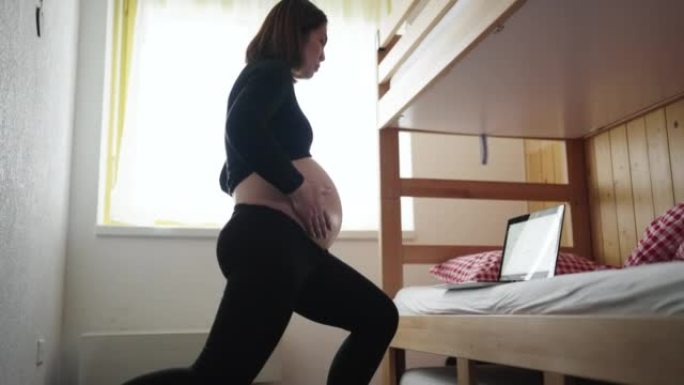 孕妇在家中用笔记本电脑在卧室锻炼