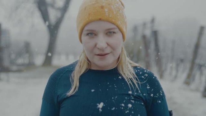SLO MO女人在雪地里穿过森林慢跑时停下来喘口气
