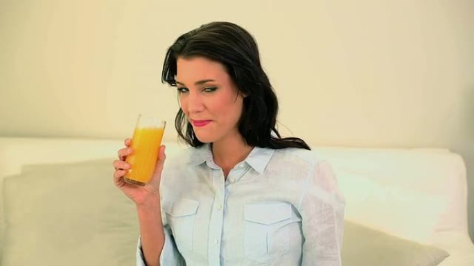 美丽的黑发女人喝一杯橙汁