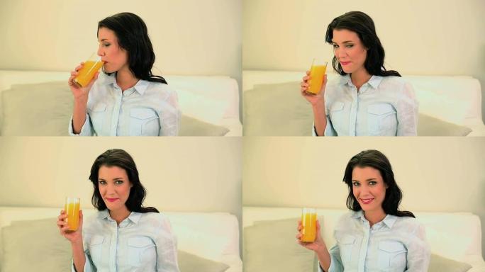 美丽的黑发女人喝一杯橙汁