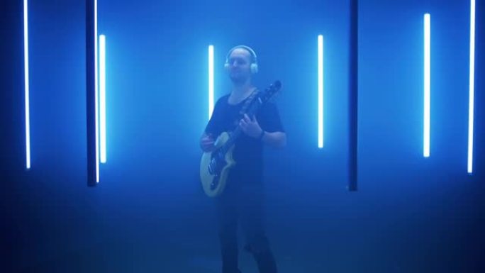 男性摇滚歌手在蓝灯圈弹吉他
