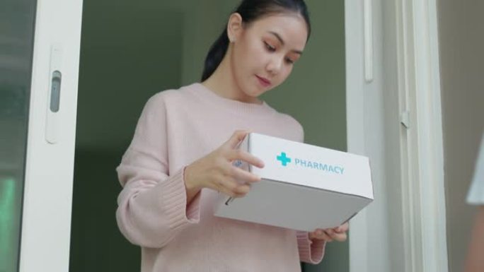 年轻的亚洲妇女收到药品药房医药箱送货上门。