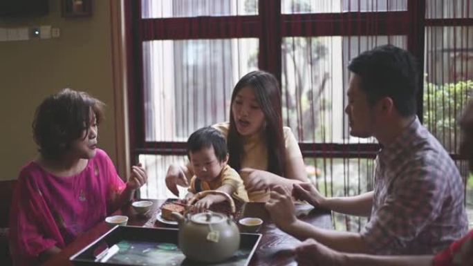 中国父亲与儿子高五岁，在下午茶聚会期间在家享用传统的中秋月饼和中国茶