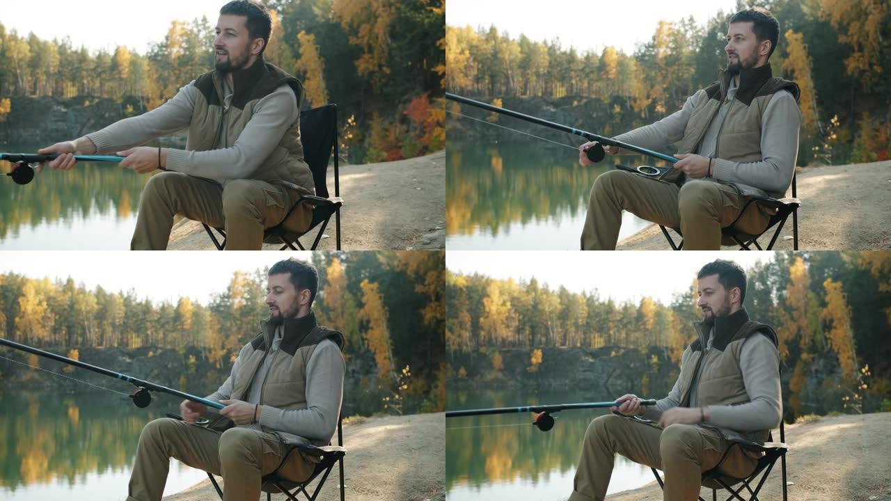 快乐的家伙钓鱼抱杆坐在舒适的椅子上独自观看美丽的风景