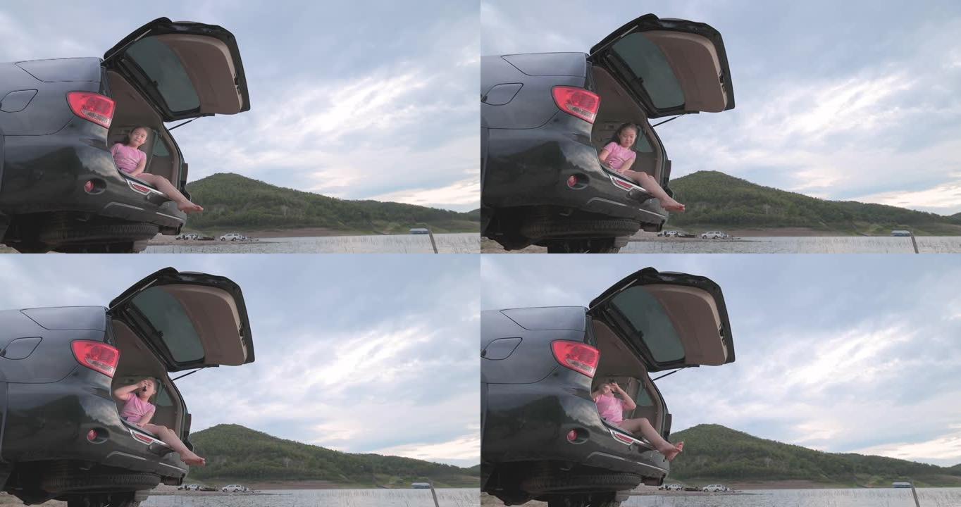 快乐的小女孩在湖边的汽车里吃饭