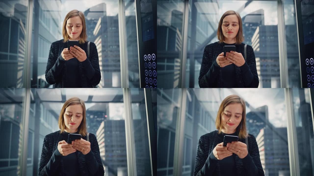 自信的年轻成年女性乘坐玻璃电梯到现代商务中心的办公室。成功的经理使用智能手机，在电梯里写信息，查看社