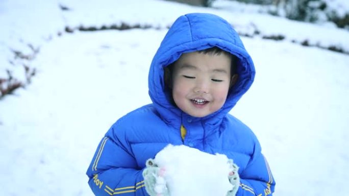 蹒跚学步的小男孩在冬天玩雪