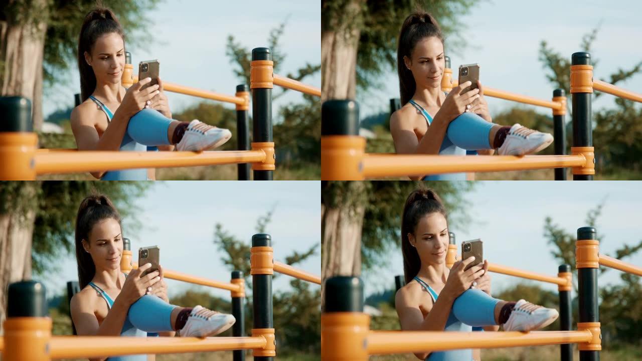 SLO MO运动女子在户外健身房休息时使用手机健身