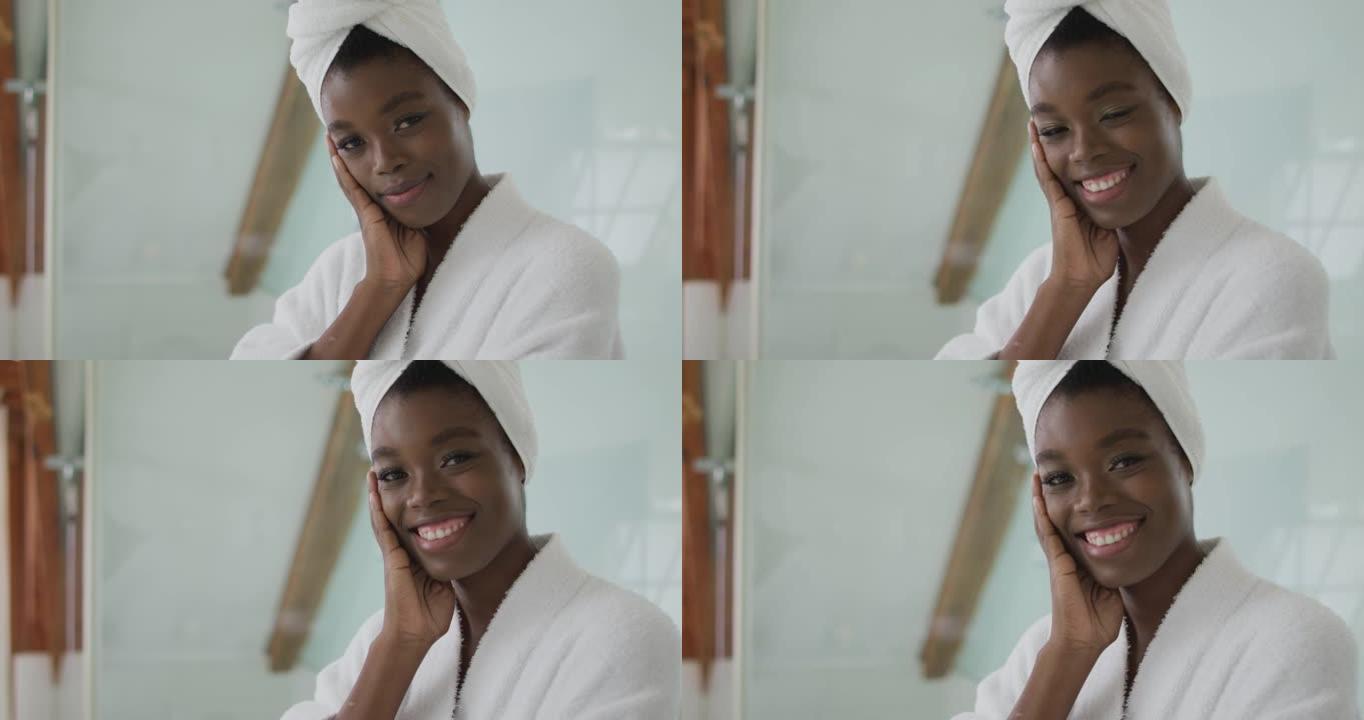 微笑的非洲裔美国迷人女人在浴室穿着长袍和头巾的肖像