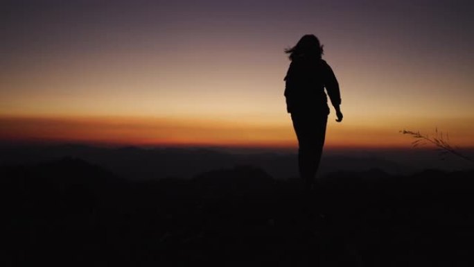 女人在日落时在大自然中的山上放松