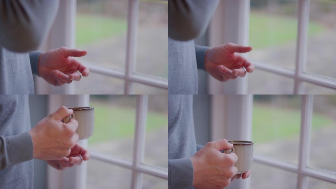 男人在家中站在窗户旁喝杯茶或咖啡的特写镜头-慢动作拍摄